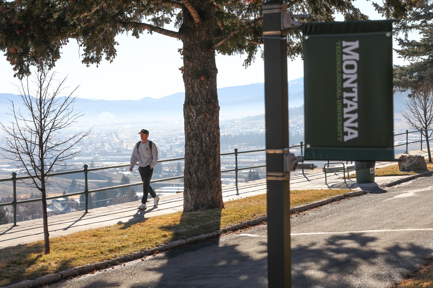 A student walks on campus with Butte in the background. 