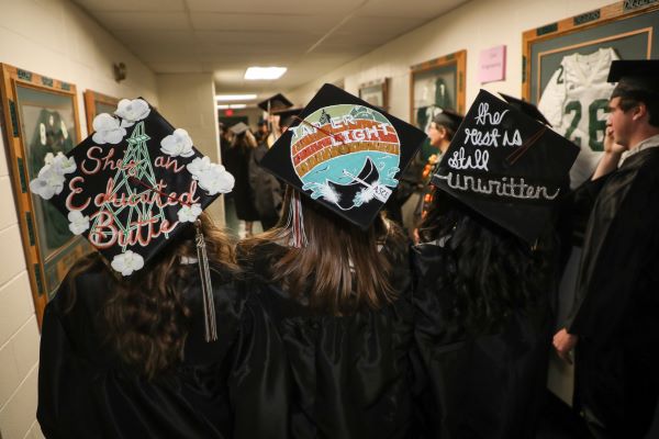 Three decorated graduation caps are worn by students