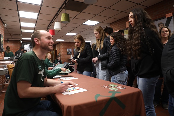 Photo of admissions rep checking student into a registration table.
