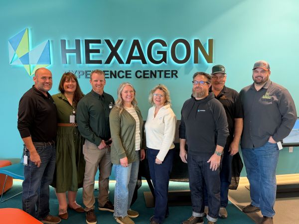 !A group of people in front of the Hexagon Experience Center sign