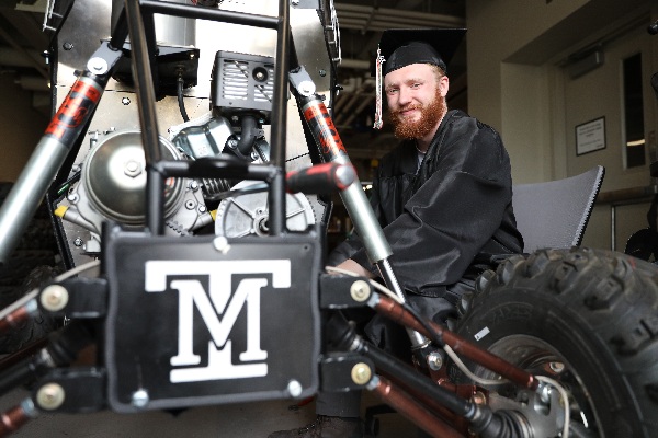 Francis Rogers with the Baja buggy, in his cap and gown