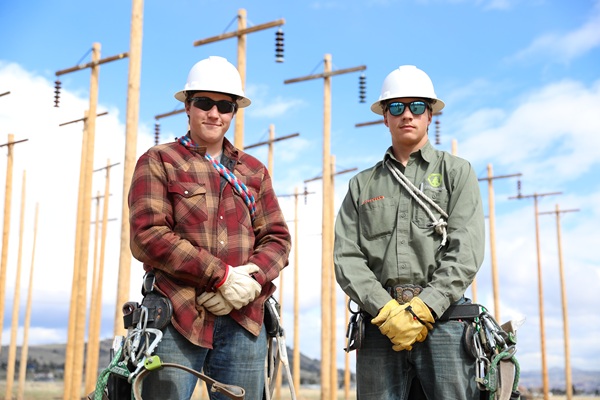 Two Montana Tech line students pose for a photo in the pole yard