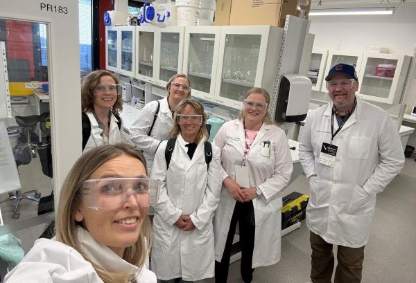 Six people in labcoats in a laboratory setting