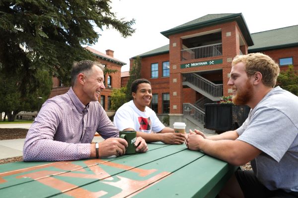 !Chancellor Cook converses with students at a picnic table