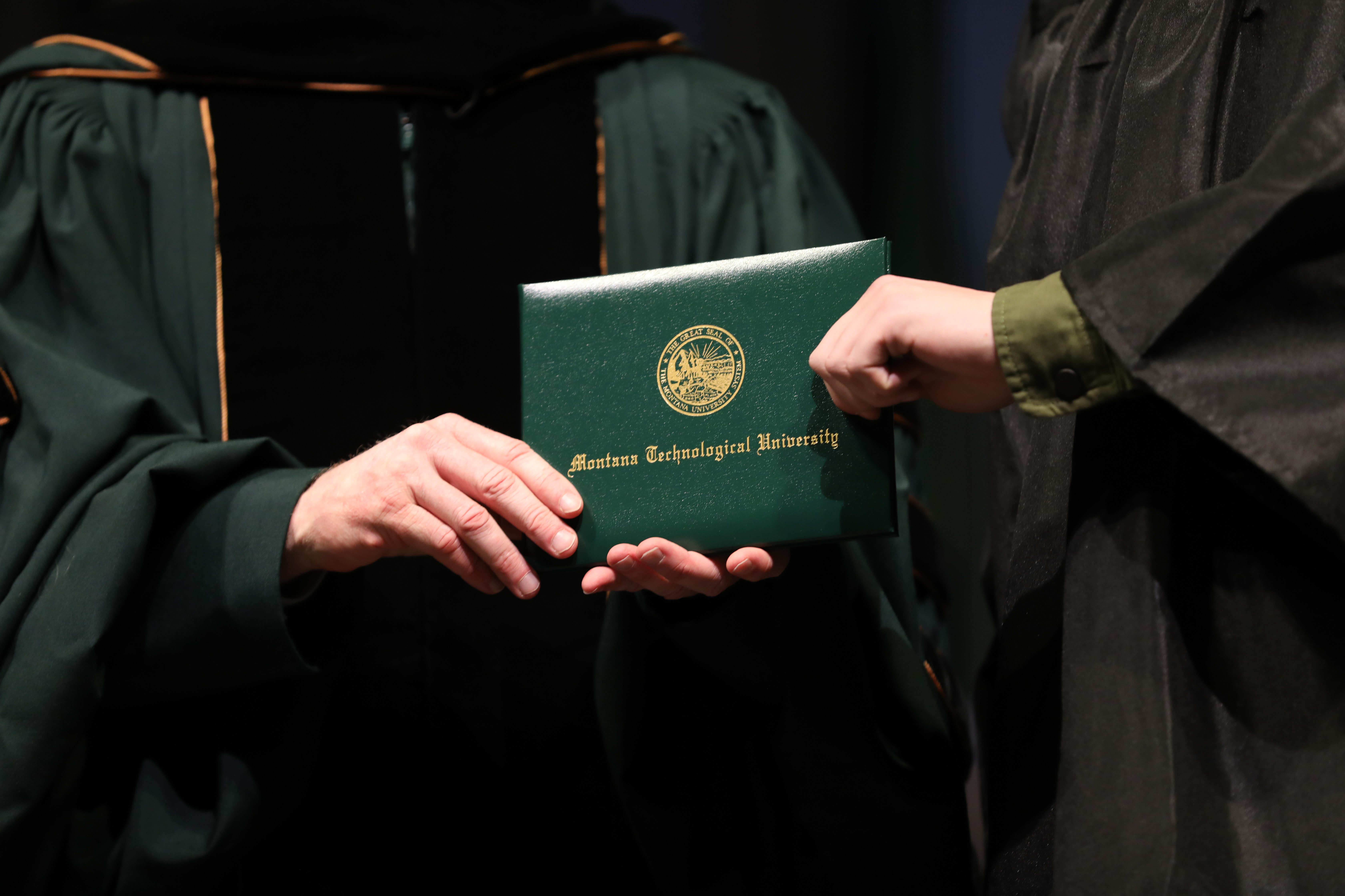 student holding degree from faculty at the graduation ceremony