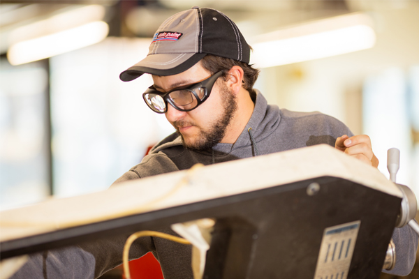 Student wearing safety goggles using mechanical engineering equipment