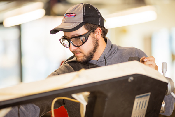 Man wearing safety goggles using mechanical engineering equipment