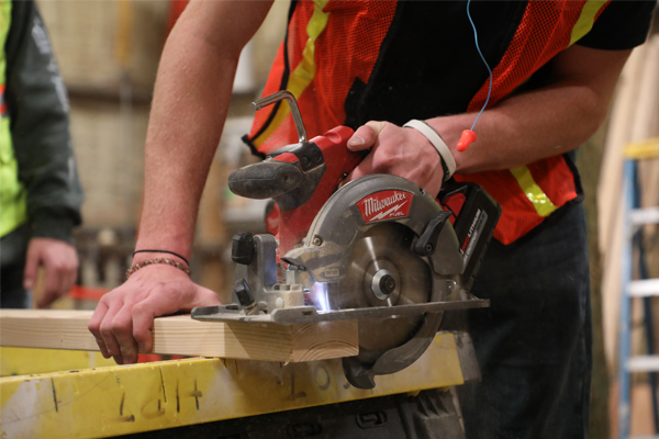 Student using a hand saw to cut wood