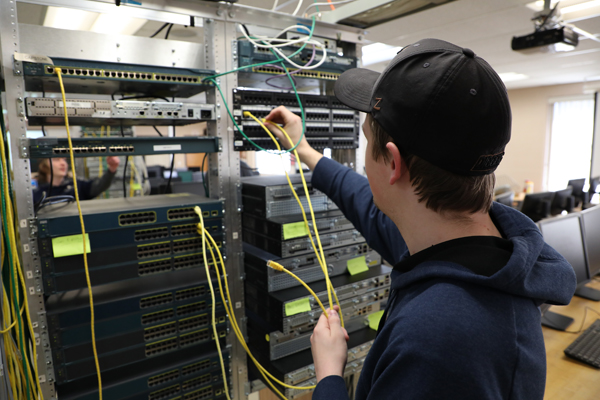 Student plugging cables into a network switch