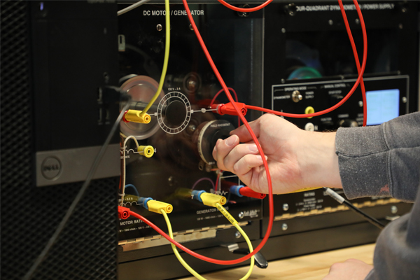 Hand adjusting a dial on electrical engineering equipment