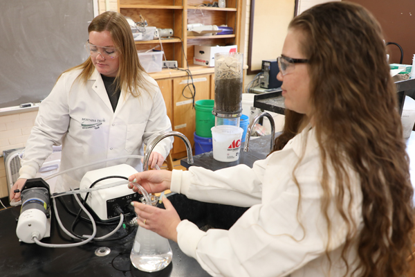 Two female students using environmental equipment in a lab