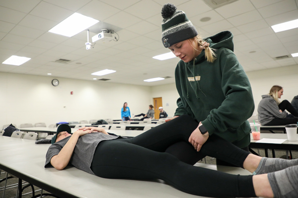 Student helping someone stretch their leg