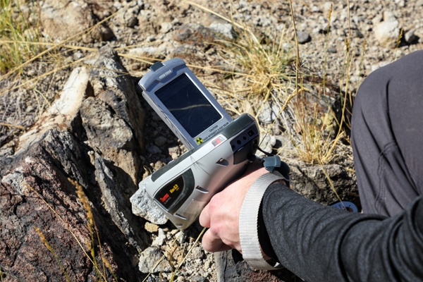 Hand holding a piece of equipment to sample rocks