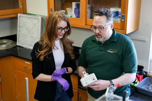 Faculty member showing a student how to use safety equipment