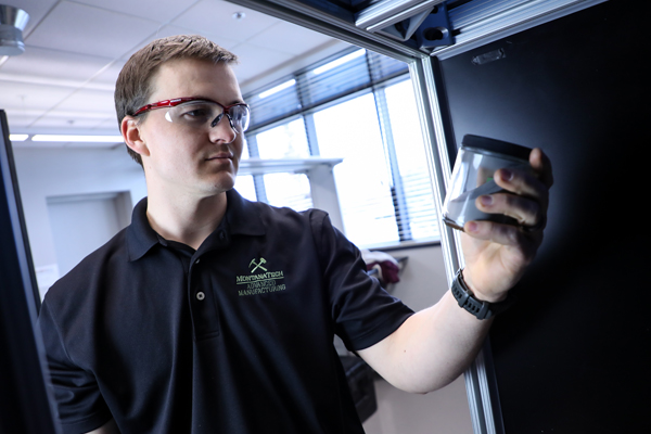 Student wearing safety glasses holding a jar in a mechanical engineering lab