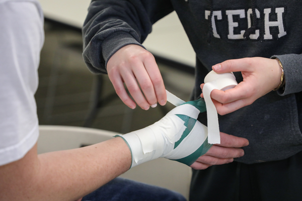 Student applying sports tape to a hand