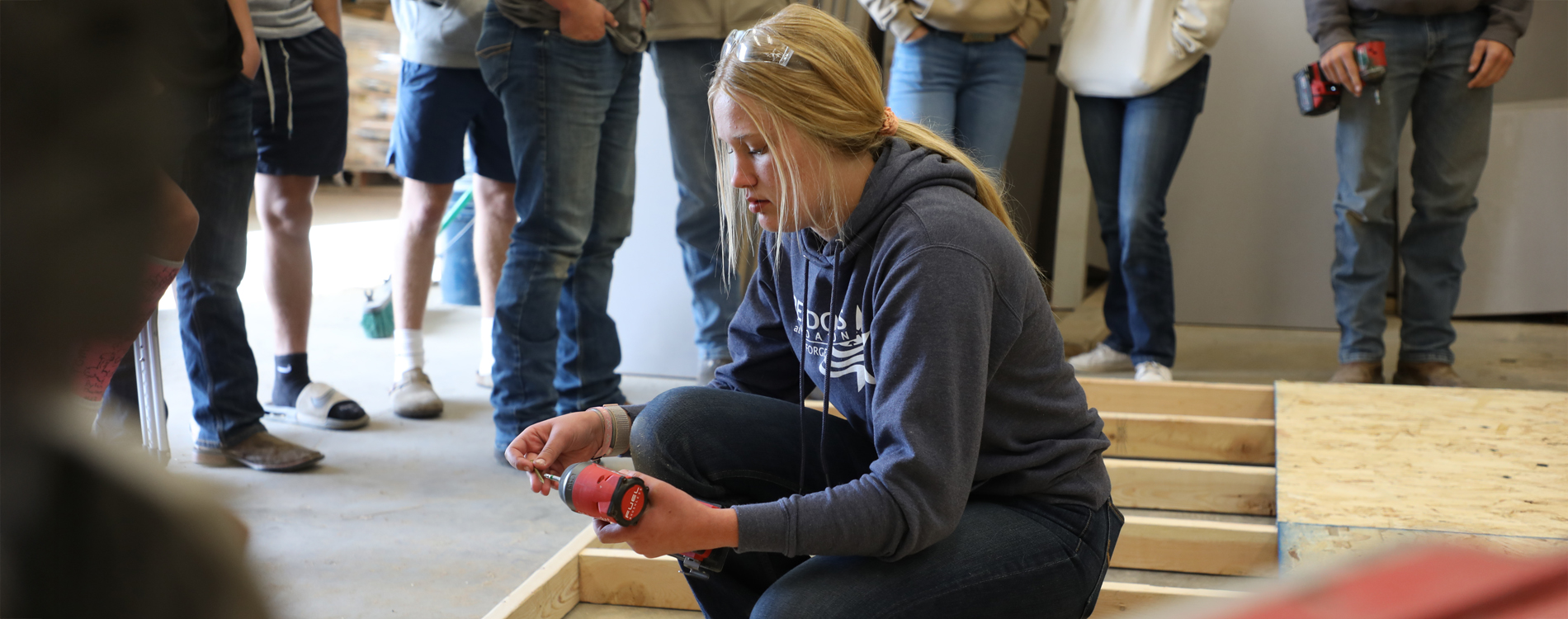 Female student putting a screw on a drill