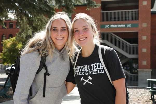 !2 students pose for a photo in the courtyard