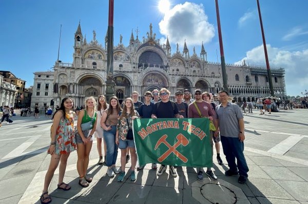 !students hold Montana Tech flag in front of castle