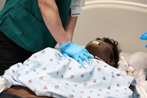 !A student administers CPR to a mannequin