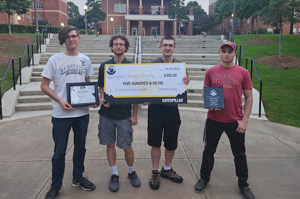 !Four students standing with a $500 check