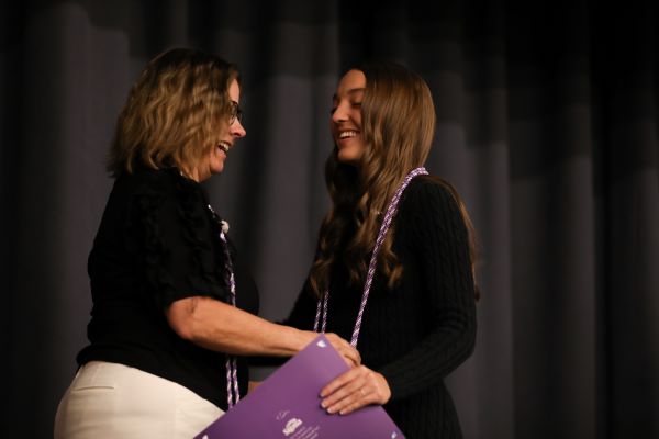 A nursing student shakes the hand of Director of Nursing Janet Coe on stage