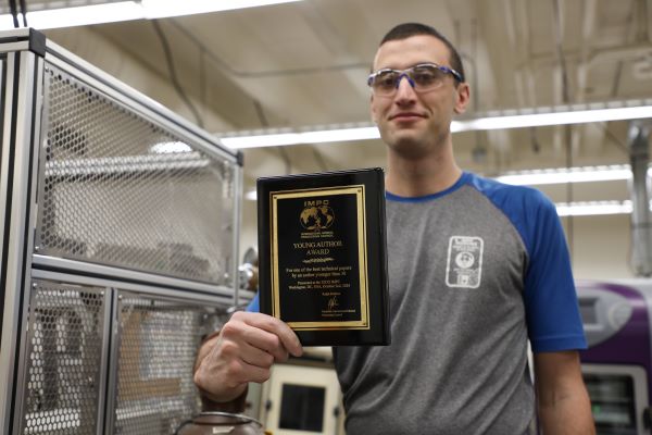 Mitchell Harvey displays a plaque in a lab