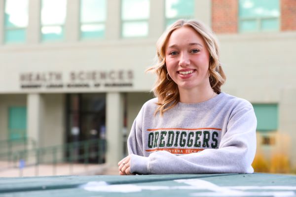 Taylor McKinley-Whitcomb poses for a photo in front of the Health Sciences building