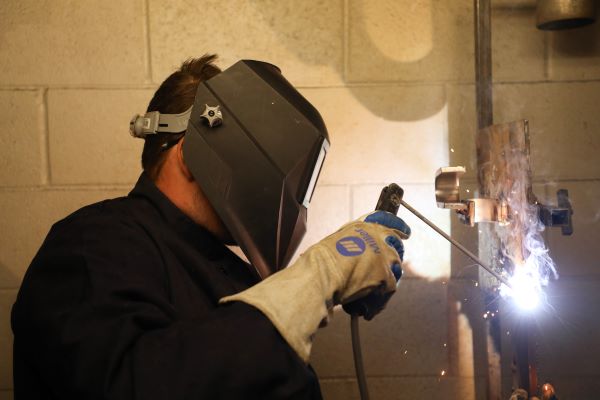 John Gamble in a welding helmet, welding