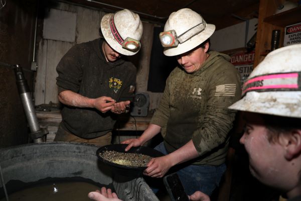 Three students pan for gold