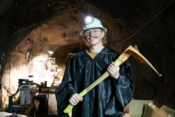 Johannes Chandler in his graduation gown and hardhat in the underground greenhouse