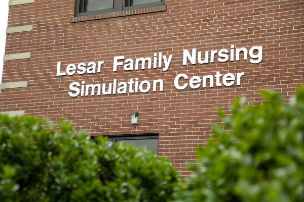 Signage on the side of a building that reads "Lesar Family Nursing Simulation Center"