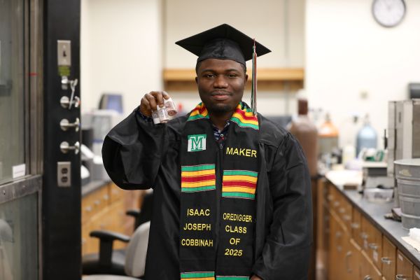 Isaac Joseph Cobbinah in a cap and gown in the lab.