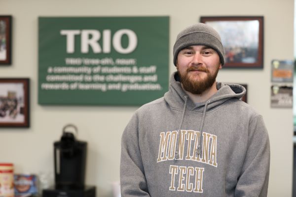 Riley Huckins  stands in front of the TRIO sign