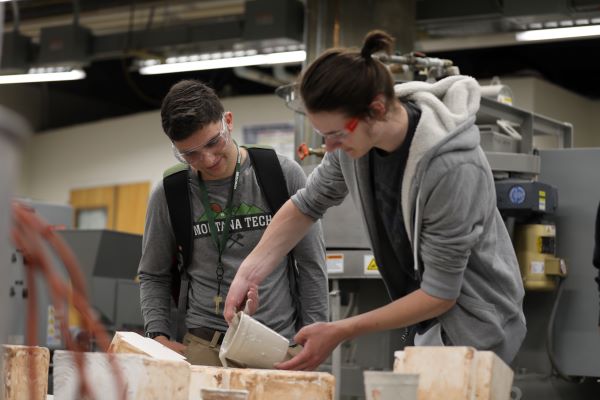 Two students pour a gooey substance