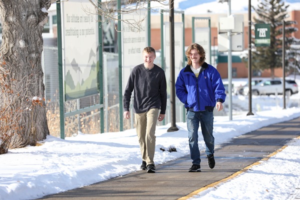 Two students walk on campus. 