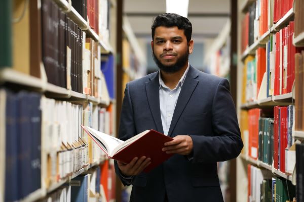 Umaer Zaki poses for a photo in the library