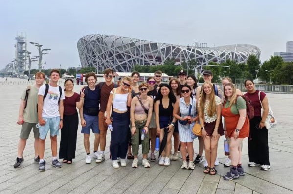 Students pose for a photo in front of the National Stadium, also known as the Bird's Nest