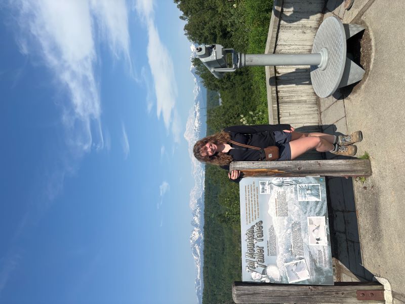 A student at a scenic overlook with mountains in the background.