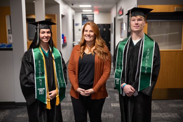 Anni Anderson with two students in caps and gowns