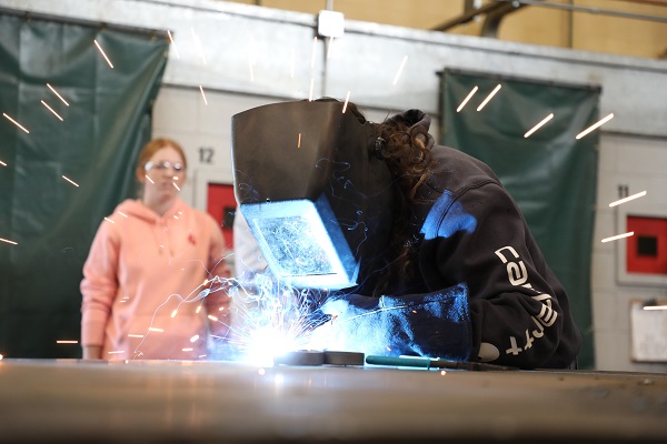 Sparks fly as a student in a helmet welds.