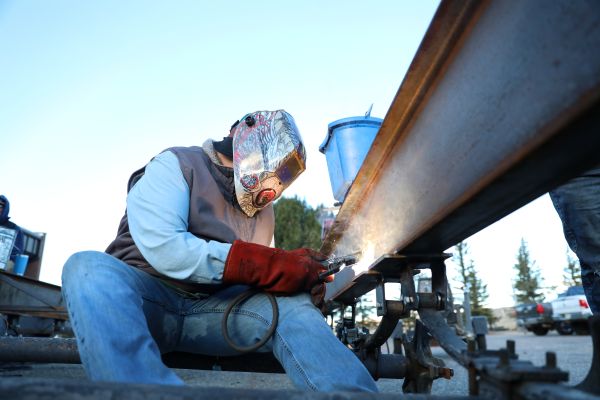 A welding student works on a trailer