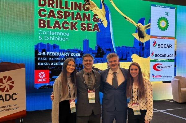 Students pose in front of an event poster