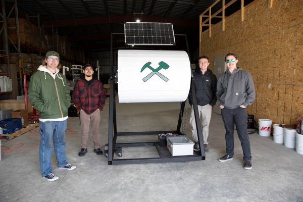 Four students pose with their solar-powered composter.