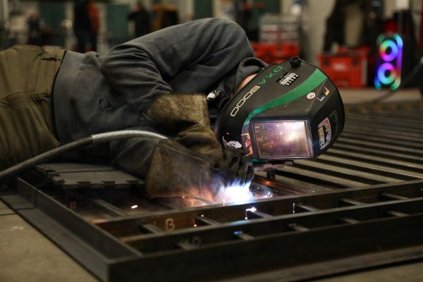 A welder works on a a metal fence