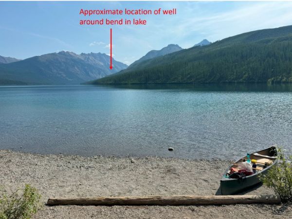 Kintla Lake well site photo with canoe in foreground. Text that says "Approximate location of well  behind the lake" with arrow. 