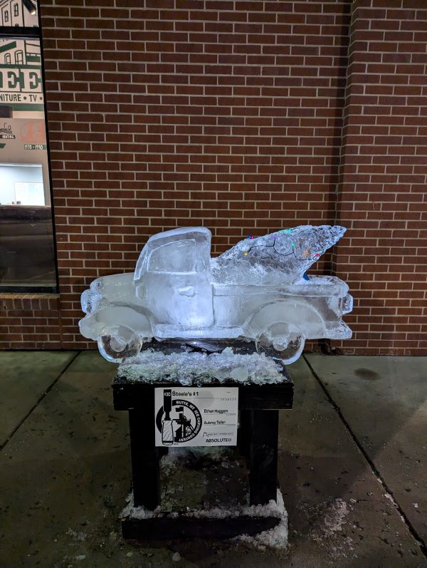 Ice sculpture of a truck carrying a Christmas tree.