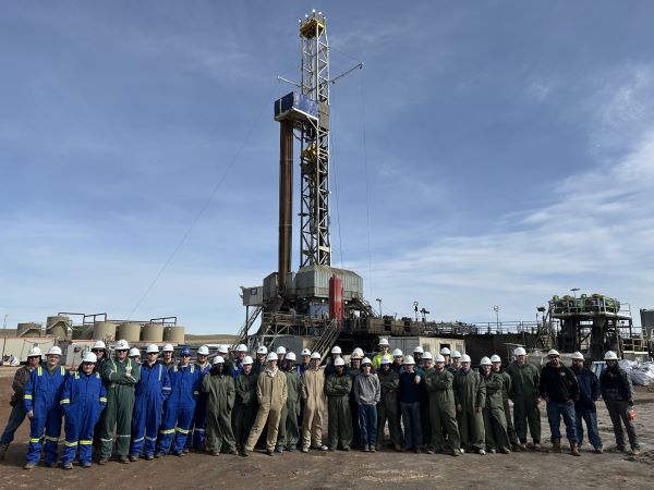 A group of students stand in front of a drilling rig run by Continental Resources