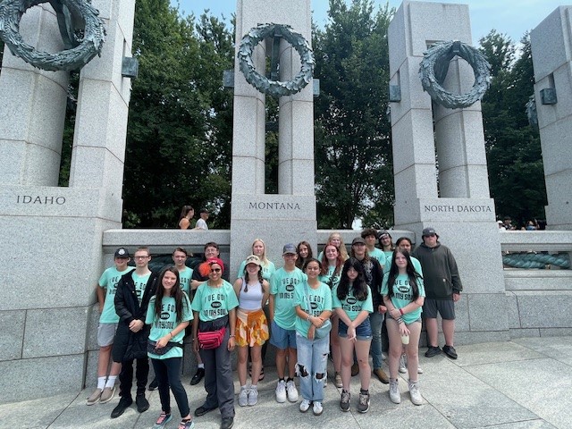 Students pose in front of a Montana pillar.