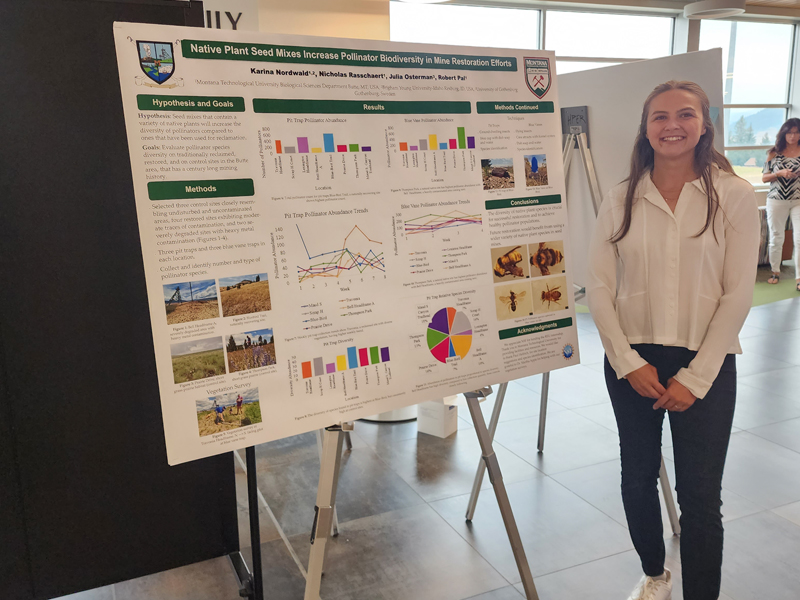 Girl standing in front of a poster board for her REU project on native plant seed mixes.